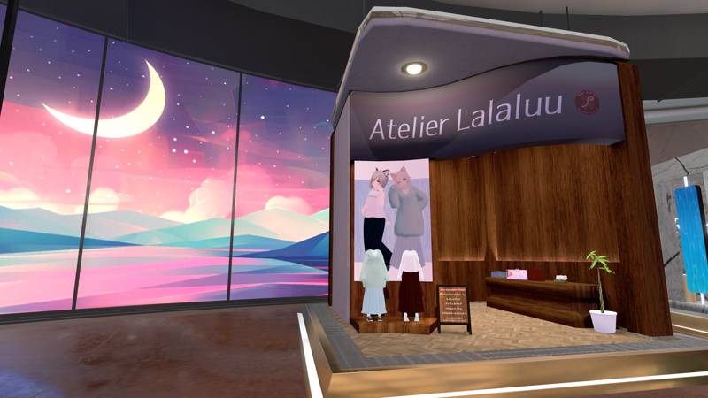 Atelier Lalaluu’s booth inside a mall. Clothes and accessories are displayed on a platform and table made of wood, along with a potted Pachira plant on the side.