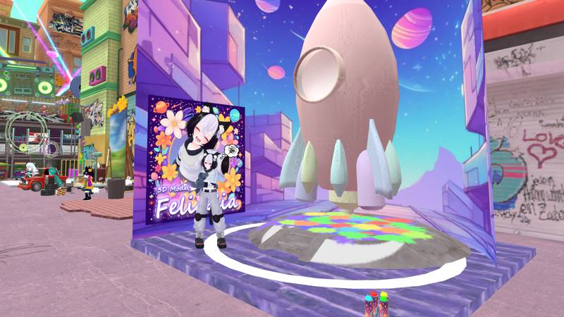 Betabgt’s booth, in a graffiti-filled street. A half-colored rocket model is in a space-themed background, with a character beside it in a thinking pose.