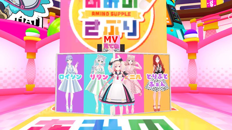 A girl with pink twintails poses in front of the colorful AminoθSupple booth, beside the character stands of each of the group’s members.